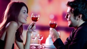 Young happy amorous couple celebrating with red wine at restaurant